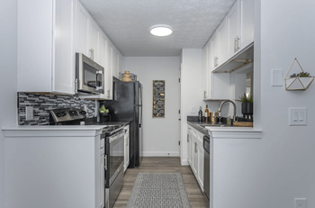 a kitchen with white cabinets and a black refrigerator at Hilltop Apartments, Cincinnati